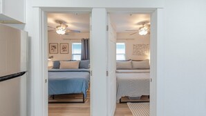 A bedroom with two beds, a ceiling fan, and a window with curtains. - Charming Modern Cottage, Downtown @pinpointstays (Coos Bay)