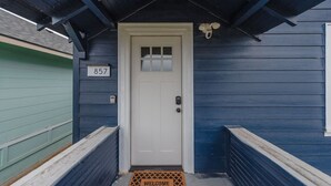 A blue house with a white door, a welcome mat, and a number 857 sign. - Charming Modern Cottage, Downtown @pinpointstays (Coos Bay)