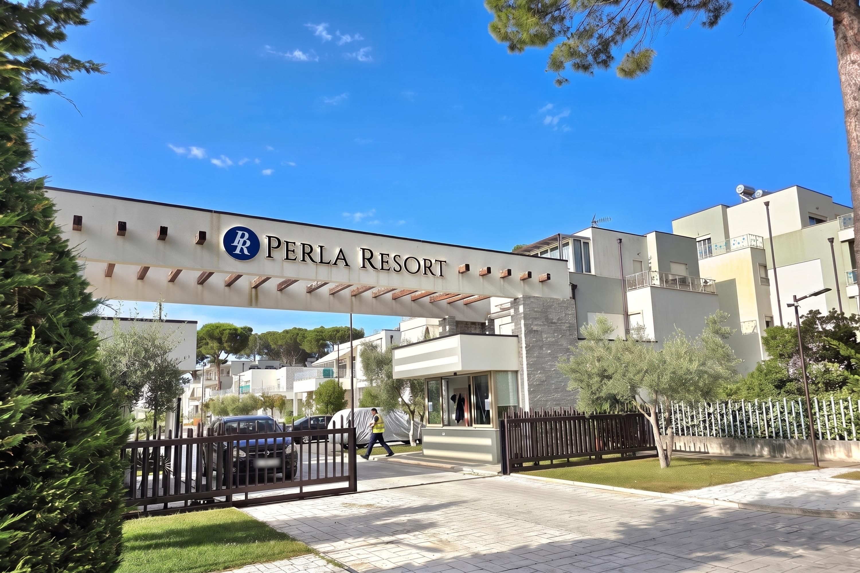 L'entrée du Perla Resort, avec un ciel dégagé et une enseigne au-dessus du portail.