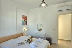 A hotel room with a bed, bedside table, mirror, wall art, and an air conditioning unit. - Serenity Penthouse, Lalzit Bay, Albania (Lalzit Bay)