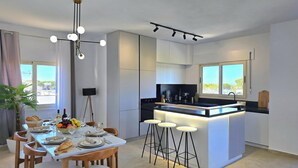 A modern kitchen with a central island, bar stools, and a dining area with a table set for four.