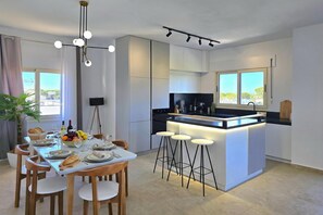 A modern kitchen with a central island, bar stools, and a dining area with a table set for four.