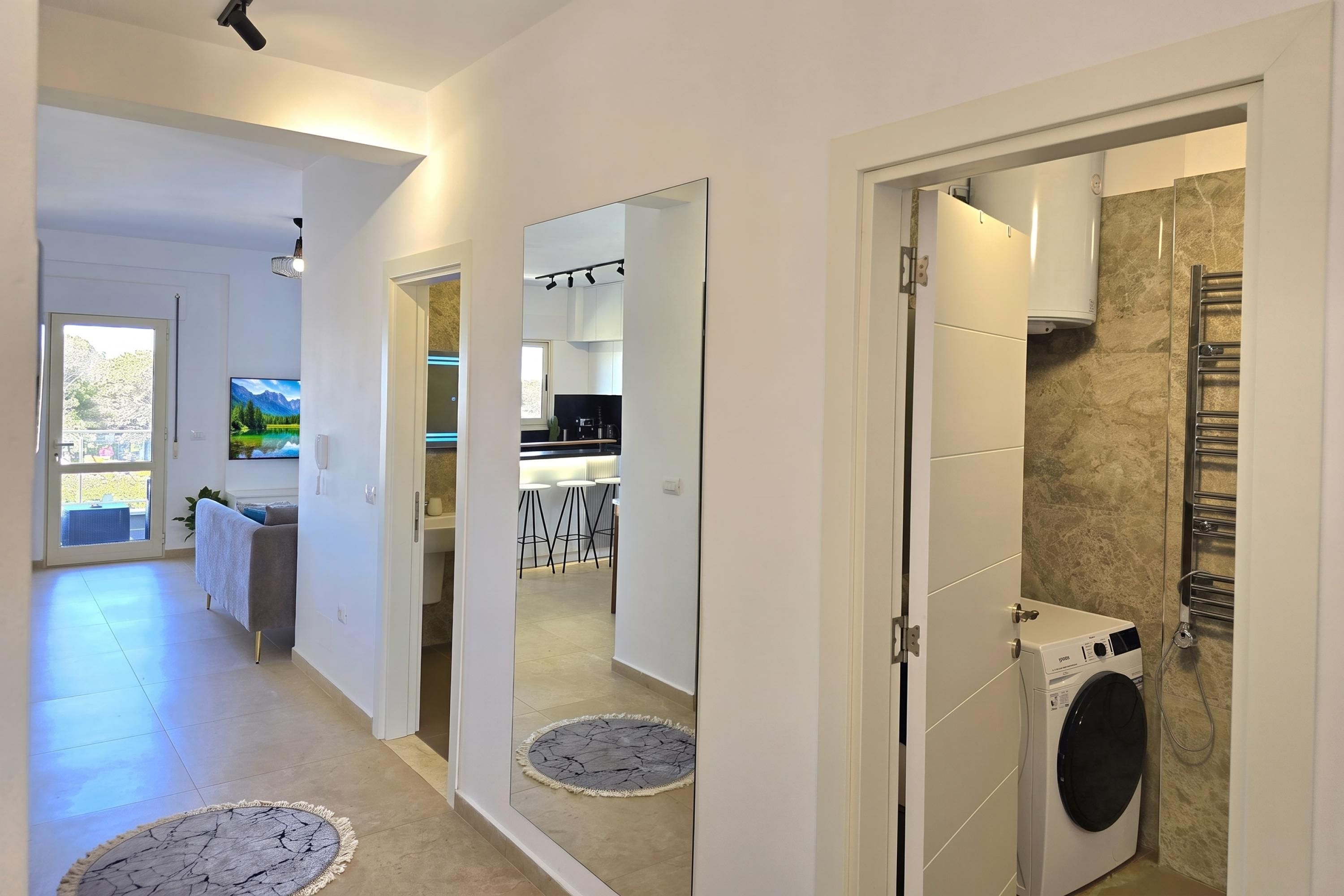 Ein modernes Interieur mit Küche, Essbereich und einer Waschküche mit Waschmaschine.