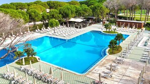 A large swimming pool with multiple lounge areas and a view of the sea.