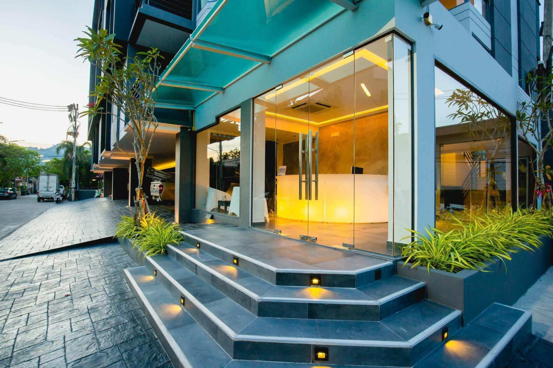 A modern building with a reception desk, glass doors, and a staircase leading to the entrance.