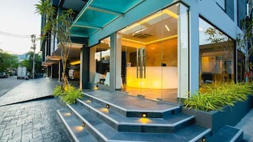 A modern building with a reception desk, glass doors, and a staircase leading to the entrance.