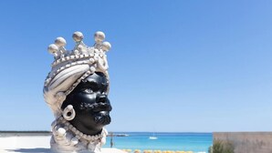 A statue with a crown and beads, set against a beach backdrop with clear skies. - Hotel Piccolo Mondo (San Vito Lo Capo)