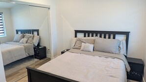 A bedroom with a bed, a nightstand, a mirror, and a ceiling fan. - Guesthouse in Anaheim - Monthly Rental (Anaheim)
