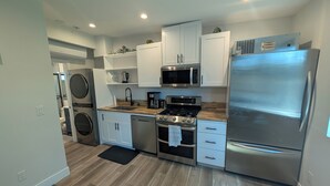 A modern kitchen with white cabinets, stainless steel appliances, and a wooden countertop. - Guesthouse in Anaheim - Monthly Rental (Anaheim)
