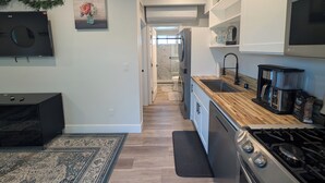 A modern kitchen with a stove, sink, and coffee maker. - Guesthouse in Anaheim - Monthly Rental (Anaheim)