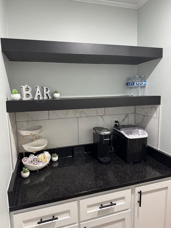 A kitchen with a black countertop, white cabinets, a coffee maker, and decorative items on the shelves. - Wonderful 3-bedroom house 2-Full Bath 2-Living Room Game Room & Barn in Fairburn (fairburn)