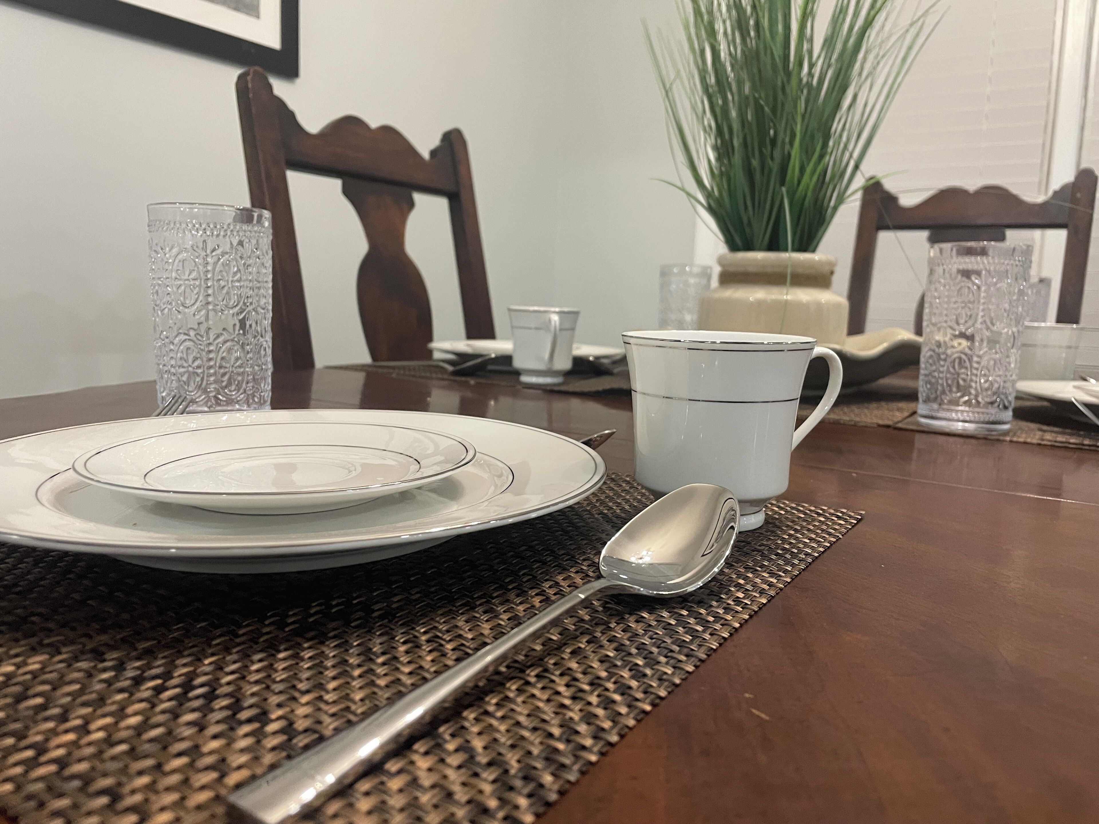 A dining table set with plates, a cup, and a spoon.