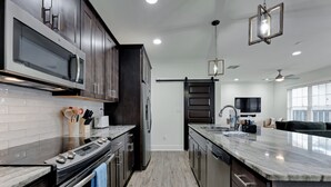 Una cocina moderna con armarios de madera oscura, una isla grande, electrodomésticos de acero inoxidable y una puerta corrediza tipo granero.