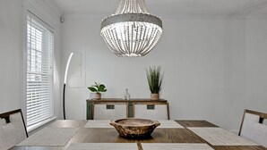 Comedor con mesa de madera, un cuenco decorativo en el centro, una araña y una consola con plantas.