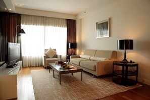 A modern living room with a flat-screen TV, a sofa, a coffee table, and a lamp. - Hotel Kukdo (Seoul)