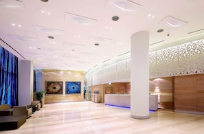 A hotel lobby with a reception desk, seating area, and decorative wall panels. - Hotel Kukdo (Seoul)