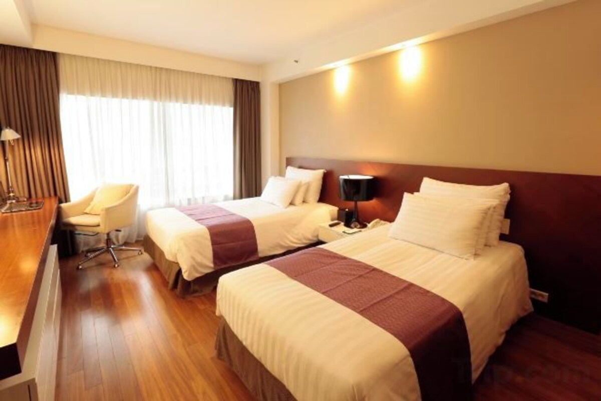 A hotel room with two beds, a desk, and a chair.
