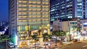 A modern hotel building with a prominent sign, multiple floors, and a well-lit facade. - Hotel Kukdo (Seoul)