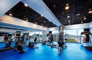 A gym with cardio machines, weightlifting equipment, and a large window with a city view. - Hotel Kukdo (Seoul)