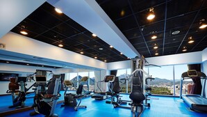 A gym with cardio machines, weightlifting equipment, and a large window with a city view. - Hotel Kukdo (Seoul)