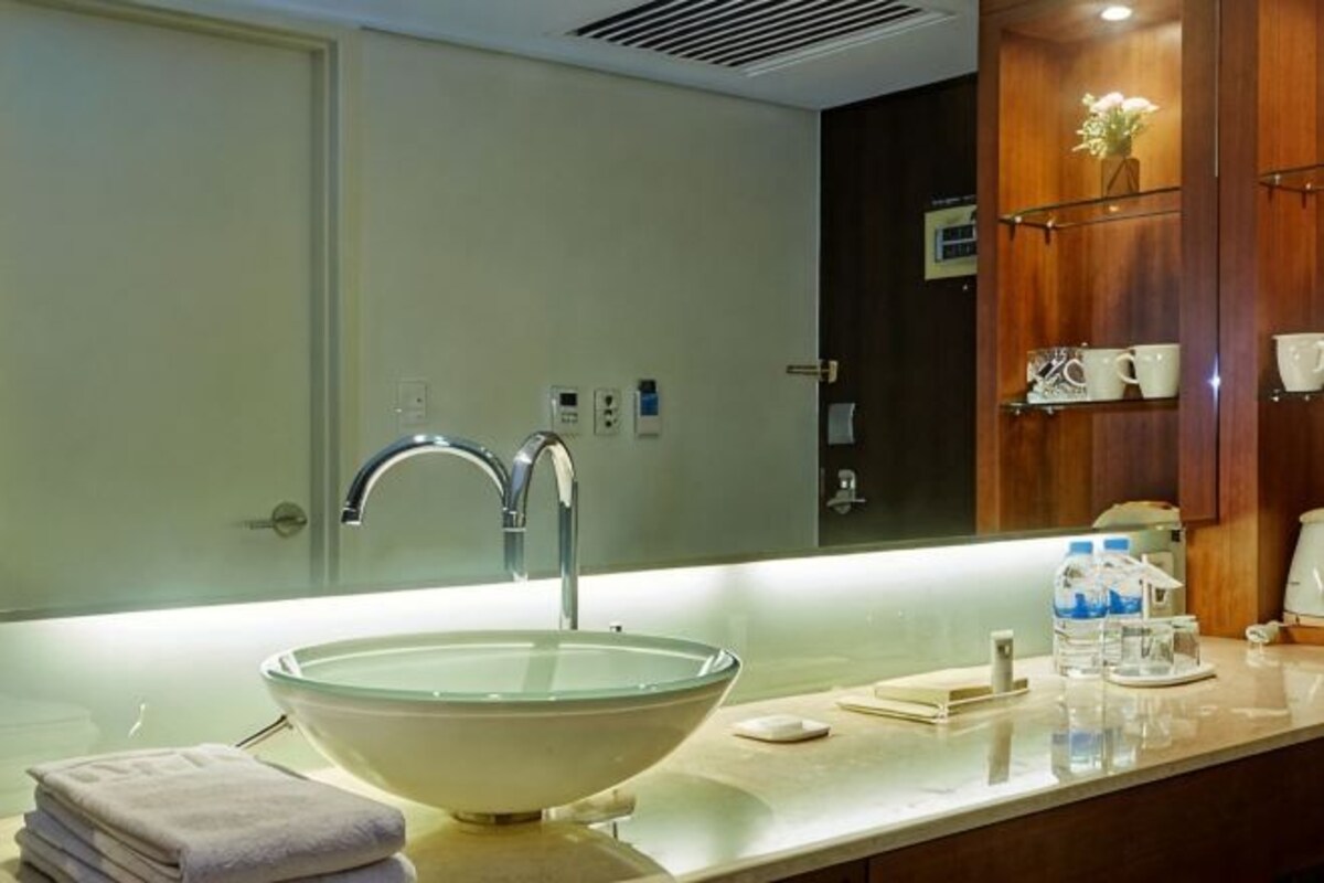A modern bathroom with a large glass sink, a mirror, and a wooden vanity.