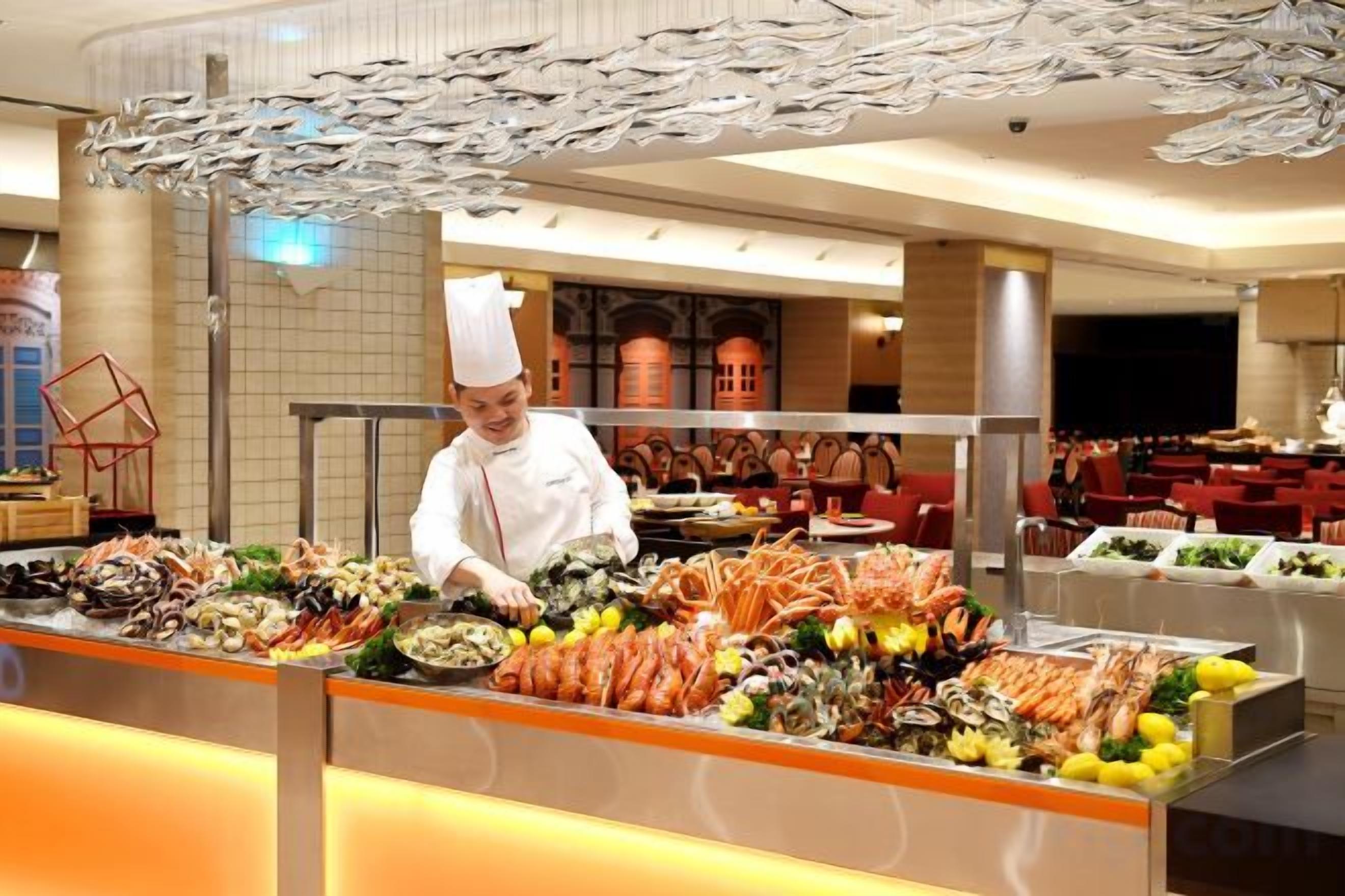 Een kok bij een buffet met diverse zeevruchten en groenten.