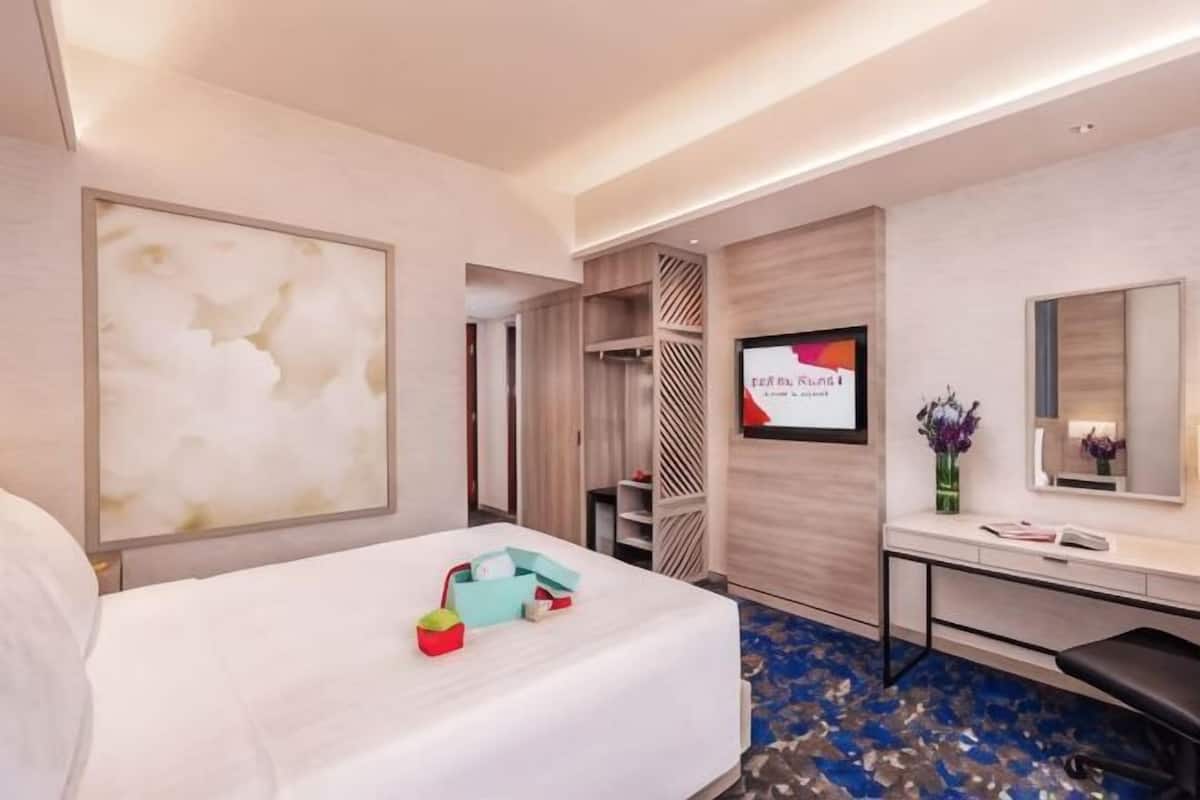 A hotel room with a bed, a desk, a TV, and a mirror.