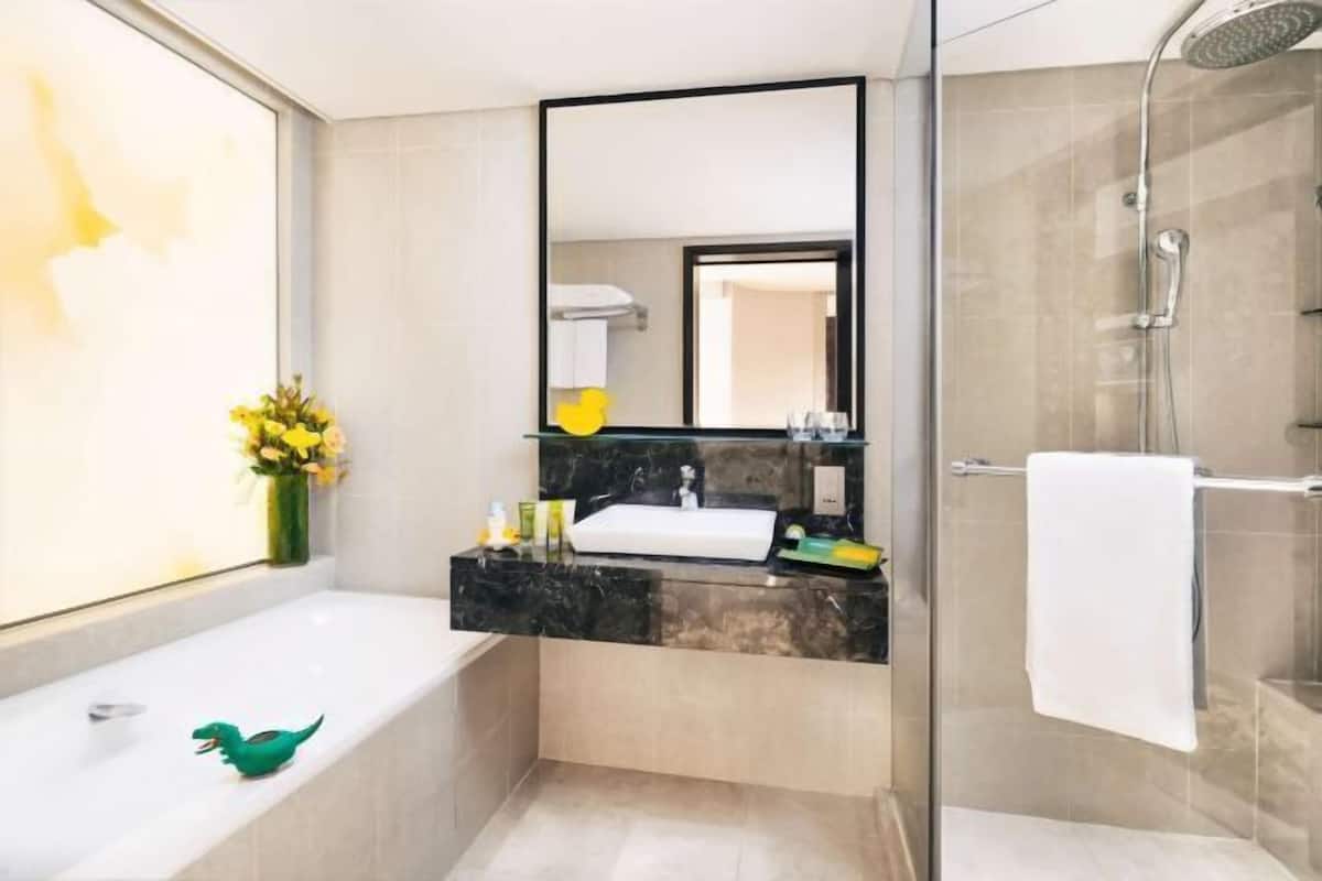 A modern bathroom with a bathtub, a glass shower enclosure, a vanity with a sink, and a mirror.
