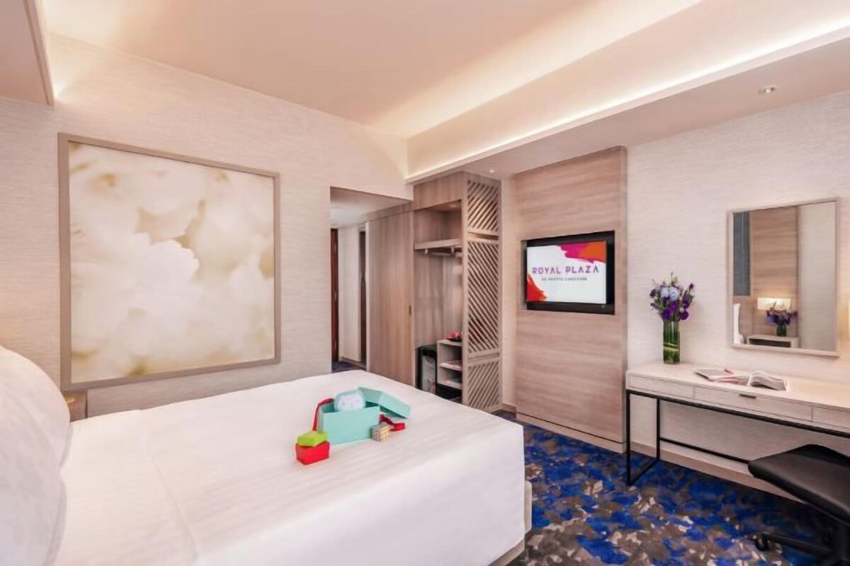A hotel room with a bed, a desk, a TV, and a mirror.