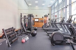 Une salle de sport équipée de tapis de course, de poids et de ballons d’exercice.