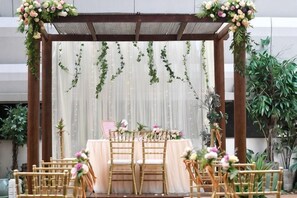 Une cérémonie de mariage en plein air, avec une pergola en bois, une table et des chaises, et des décorations florales.