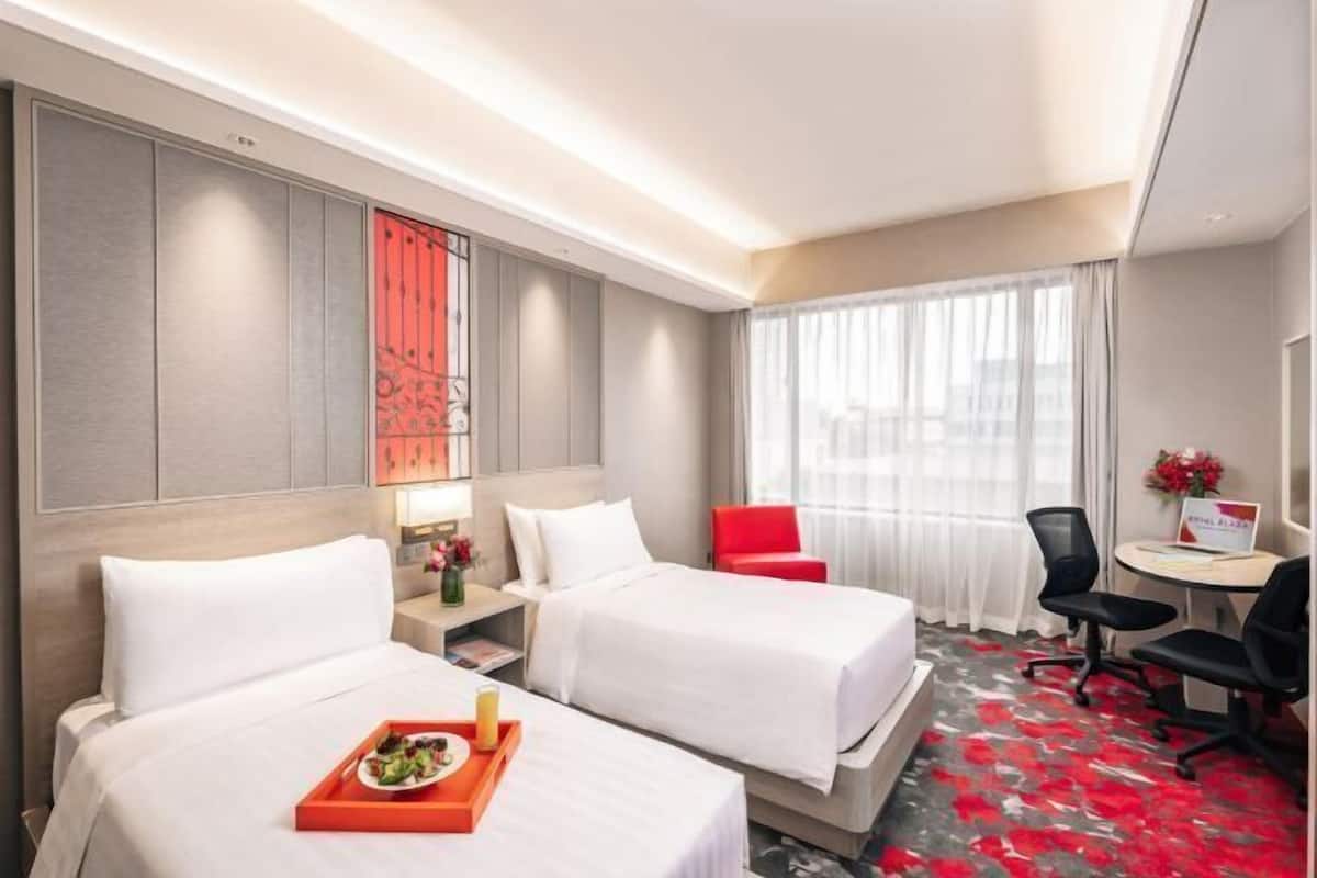 A hotel room with two beds, a desk, a chair, and a window with curtains.
