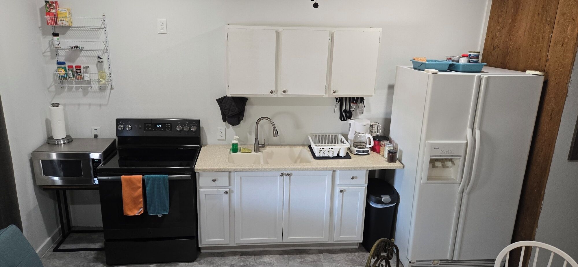 A compact kitchen with a stove, oven, sink, and a refrigerator.