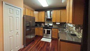 Uma cozinha moderna com armários de madeira, eletrodomésticos de aço inoxidável e painel de azulejos.