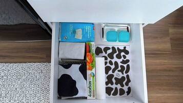 A drawer with various items including a blue box, a white towel, a black and white patterned cloth, and a roll of paper towels.