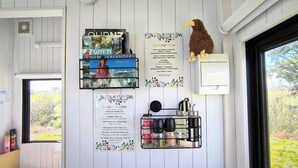 A room with a window overlooking a garden, a wall-mounted menu board, and a decorative bird.