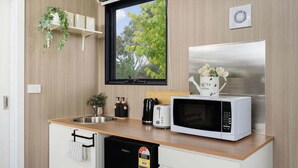 A compact kitchen with a wooden countertop, a stainless steel refrigerator, a microwave, a toaster, and a small sink.