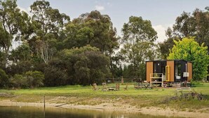A modern cabin by a lake with a deck and outdoor seating.