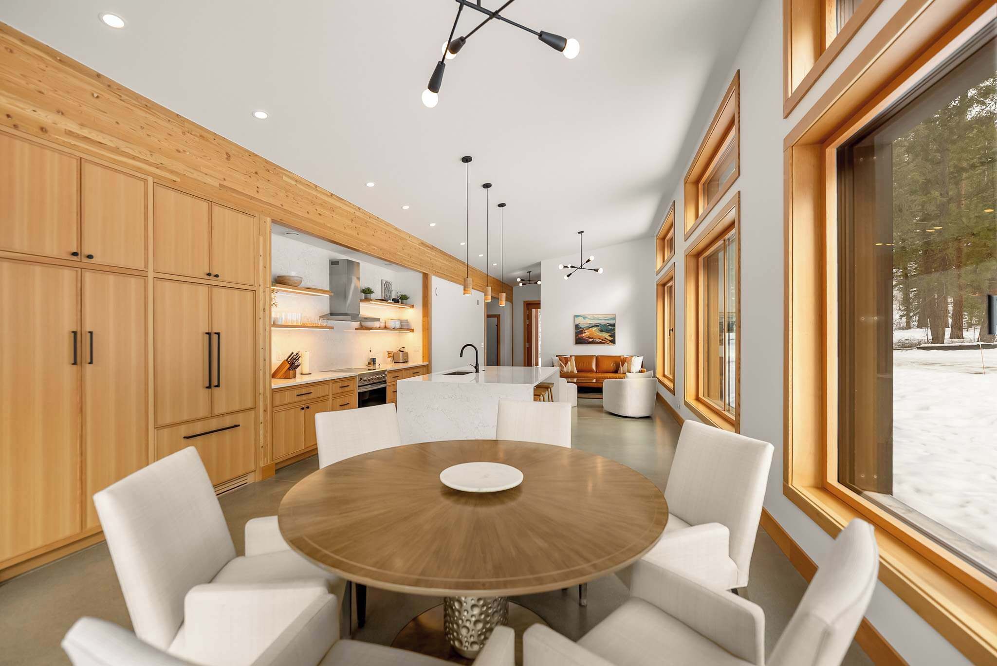 Una cocina moderna con armarios de madera, una mesa redonda de comedor e iluminación colgante.