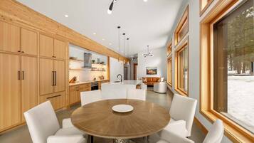 Una cocina moderna con armarios de madera, una mesa redonda de comedor e iluminación colgante.