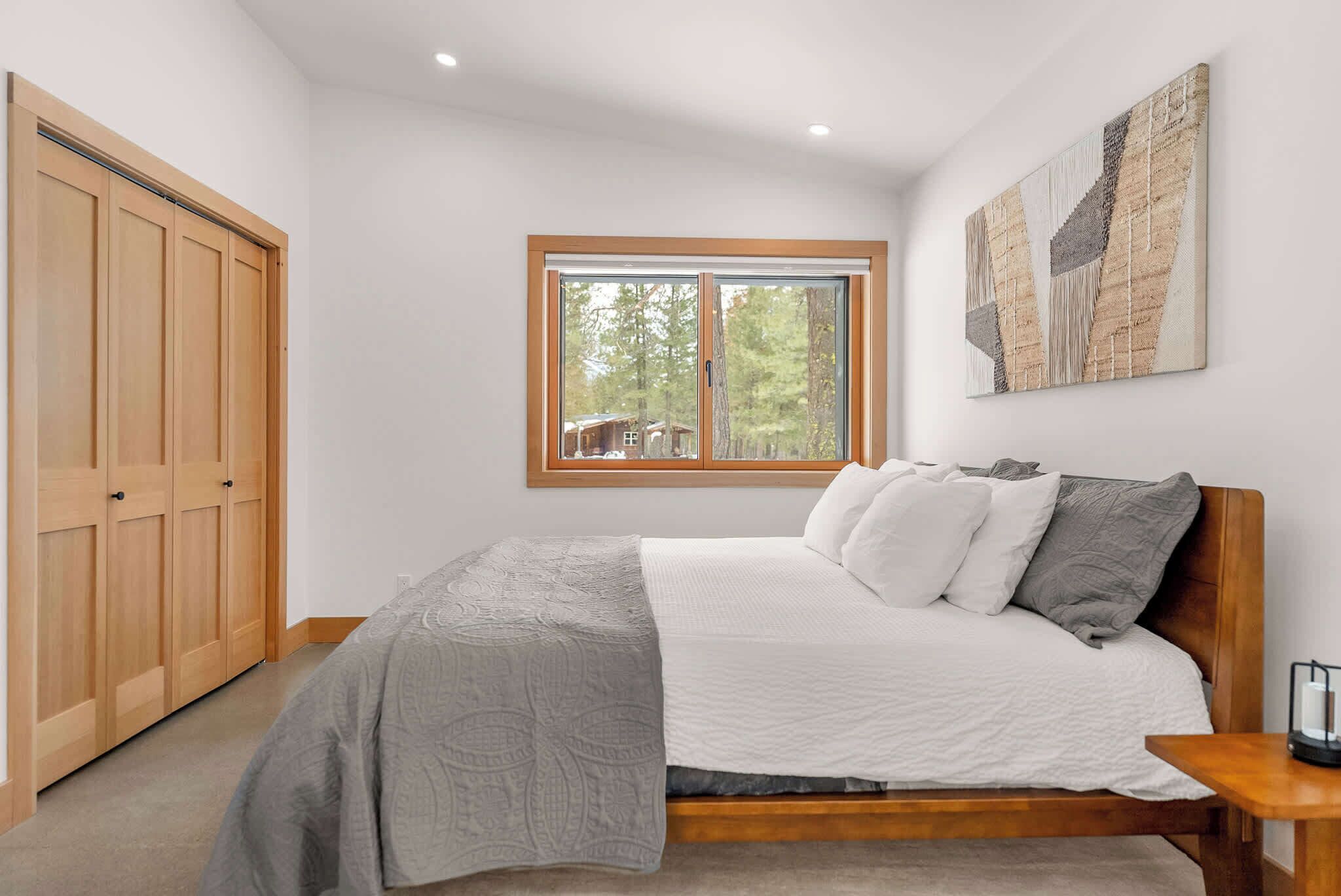 Un dormitorio con cama, ventana, armario y un cuadro en la pared.