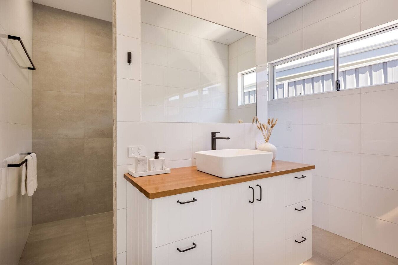 Une salle de bain moderne avec un meuble-lavabo en bois, un grand miroir et un espace douche.
