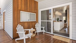 En træterrasse med to hvide Adirondack-stole og et lille rundt bord.