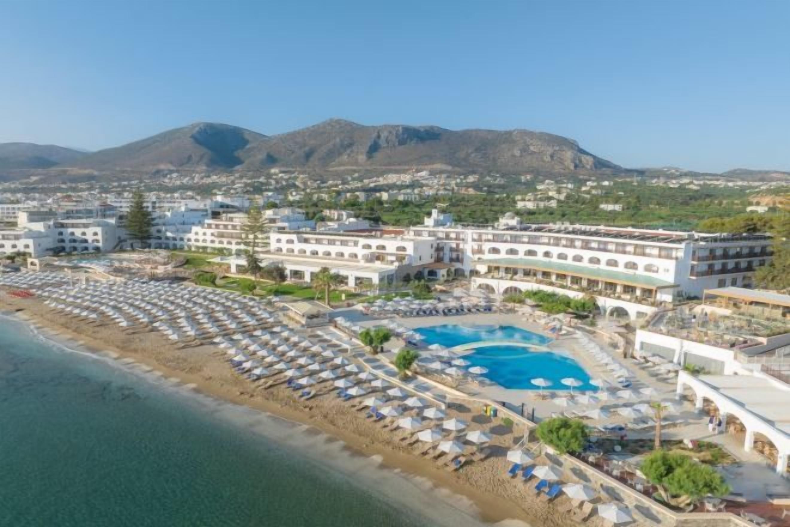 A resort with a large pool, beach area, and multiple buildings.