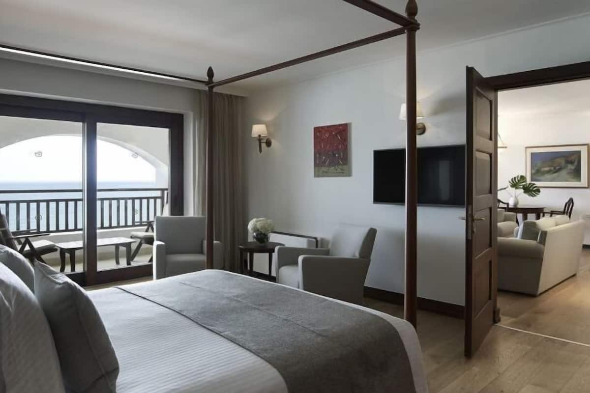 Une chambre d’hôtel dotée d’un lit à baldaquin, d’un balcon avec coin salon extérieur, d’une télévision à écran plat et d’un espace repas.