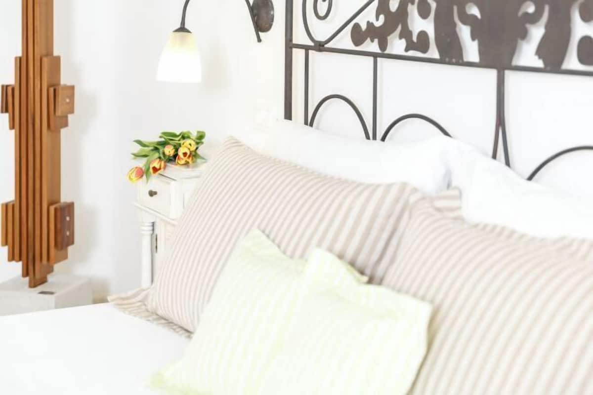 Un lit avec une literie à rayures, une table de chevet avec une lampe et un panneau décoratif au mur.