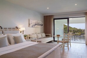 A hotel room with a bed, a sofa, a dining table, and a balcony with a view. - Creta Maris Resort (Limenas Chersonisou)