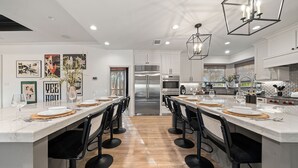 Een moderne keuken met een centraal eiland, roestvrijstalen apparatuur en een eetgedeelte met barkrukken.