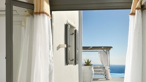 Une chambre avec un lit, une salle de bain et un balcon donnant sur la mer.