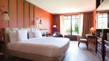 A hotel room with a large bed, bedside tables, a desk, and a chair.